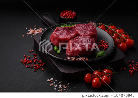 Juicy raw beef with spices, salt and herbs on a dark concrete background 104076945