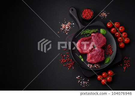 Juicy raw beef with spices, salt and herbs on a dark concrete background 104076946