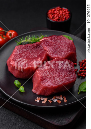 Juicy raw beef with spices, salt and herbs on a dark concrete background Juicy raw beef with spices, salt and herbs on a dark concrete background 104076955
