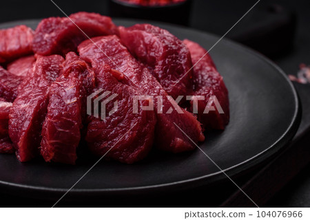 Juicy raw beef with spices, salt and herbs on a dark concrete background 104076966