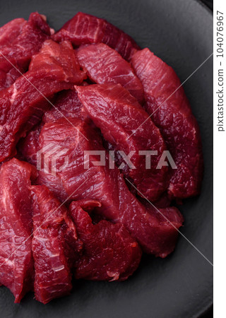 Juicy raw beef with spices, salt and herbs on a dark concrete background Juicy raw beef with spices, salt and herbs on a dark concrete background 104076967