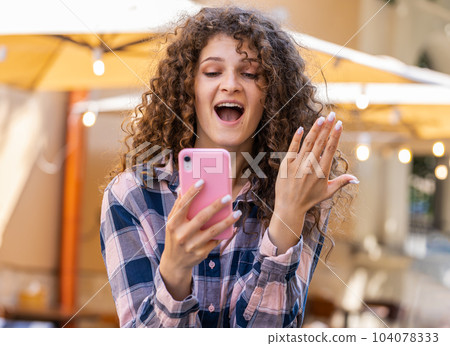 Pretty woman use mobile smartphone celebrating win good message news outdoors in urban city street Pretty woman use mobile smartphone celebrating win good message news outdoors in urban city street 104078333