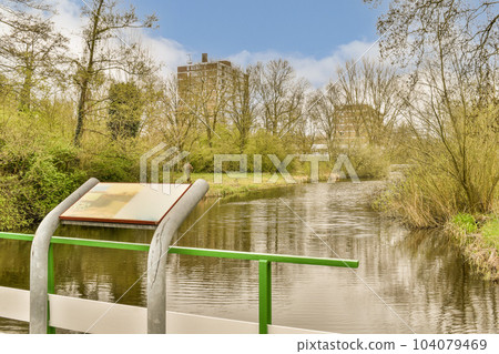 an open book on the edge of a body of water with trees and bushes in the background is blue sky an open book on the edge of a body of water with trees and bushes in the background is blue sky 104079469