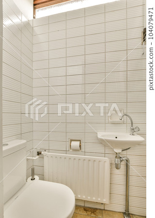a small bathroom with white tiles on the walls and floor, along with a sink and toilet in the corner 104079471