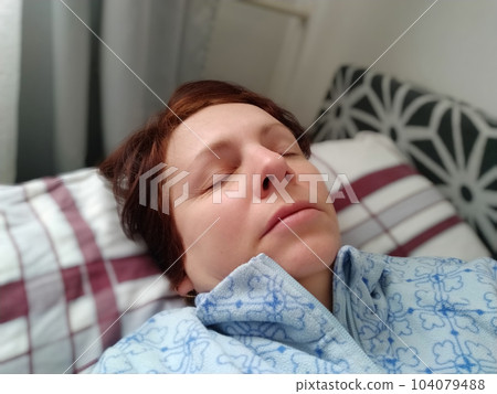Sick woman in bed. Headache, runny nose and cold. Paleness of the face and faintness of the body. Feeling unwell. The patient lies on a pillow. Loss of consciousness or shock. 104079488