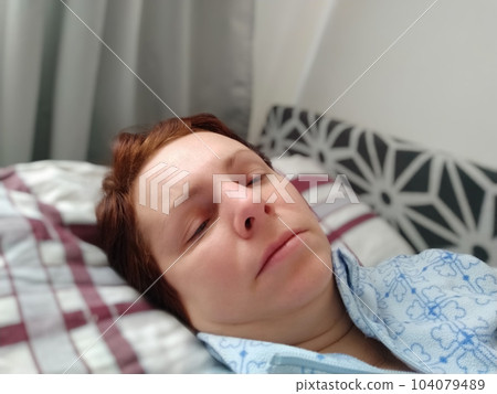 Sick woman in bed. Headache, runny nose and cold. Paleness of the face and faintness of the body. Feeling unwell. The patient lies on a pillow. Loss of consciousness or shock. 104079489