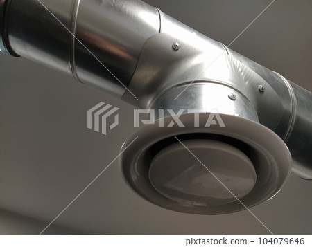 Extractor hood in a public toilet. Round metal pipe with gray air extractor. Engineering ventilation systems. Galvanized pipes under the ceiling of the room. Plastic round tip. Extractor hood in a public toilet. Round metal pipe with gray air extractor. Engineering ventilation systems. Galvanized pipes under the ceiling of the room. Plastic round tip. 104079646
