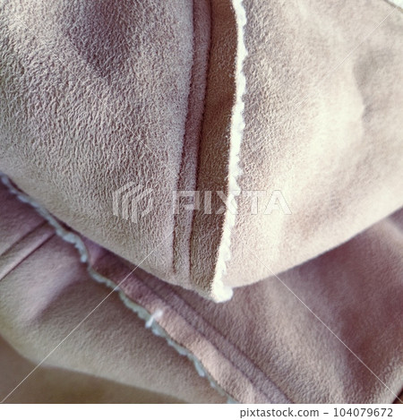 Suede outerwear with a hood. Beige faux suede with sheepskin on the fold of a demi-season garment. seams in the material. Clothing industry and fashion Suede outerwear with a hood. Beige faux suede with sheepskin on the fold of a demi-season garment. seams in the material. Clothing industry and fashion 104079672