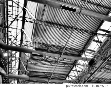 The roof of a hangar, a production hall or a sports hall. Metal structures, beams, supporting elements. Ventilation systems in large halls and rooms. Skylights. Industrial interior 104079706