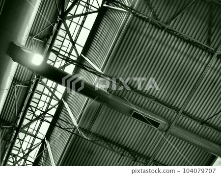 The roof of a hangar, a production hall or a sports hall. Metal structures, beams, supporting elements. Ventilation systems in large halls and rooms. Skylights. Industrial interior 104079707