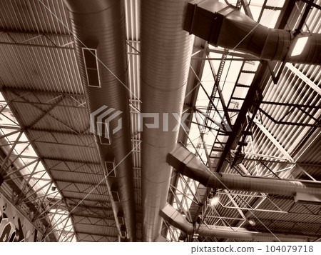 The roof of a hangar, a production hall or a sports hall. Metal structures, beams, supporting elements. Ventilation systems in large halls and rooms. Skylights. Industrial interior The roof of a hangar, a production hall or a sports hall. Metal structures, beams, supporting elements. Ventilation systems in large halls and rooms. Skylights. Industrial interior 104079718