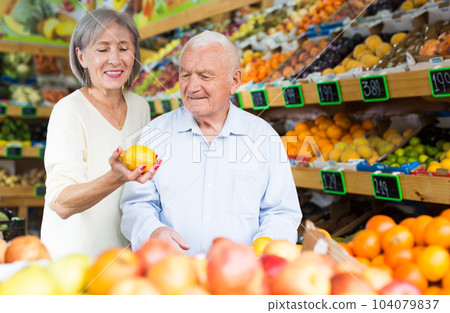 Old man and woman choosing lemons in greengrocer 104079837