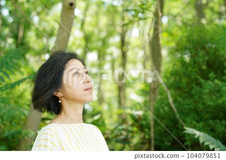清爽的中年婦女,頭髮在綠色中隨風飄揚 清爽的中年婦女,頭髮在綠色中隨風飄揚 104079851