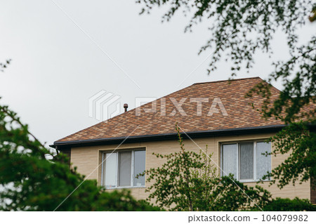 Modern house with chimney, red clay tiled roof and gable and valley type of roof construction. Roofing Construction. High quality photo. 20 May 2023 Russia Modern house with chimney, red clay tiled roof and gable and valley type of roof construction. Roofing Construction. High quality photo. 20 May 2023 Russia 104079982