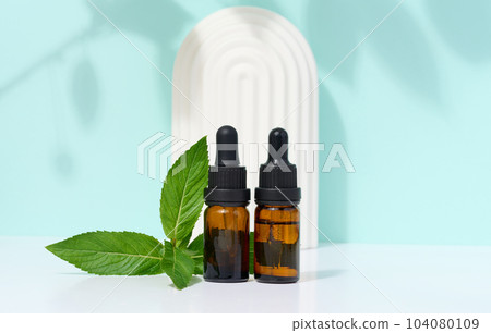 Brown glass bottle with pipette and mint leaves, container for aromatic oils and cosmetics Brown glass bottle with pipette and mint leaves, container for aromatic oils and cosmetics 104080109