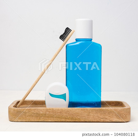 Refreshing mouthwash in a transparent plastic bottle and dental floss on a white background 104080118