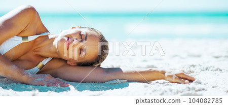 Relaxed young woman laying on beach 104082785