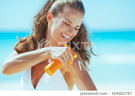Happy young woman applying sun block creme 104082787