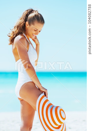 Happy young woman in swimsuit with hat enjoying on beach 104082788