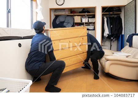 Two workers lifting a chest of drawers 104083717