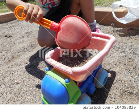 孩子在公園的沙坑玩翻斗車玩具和鏟子。 104083829