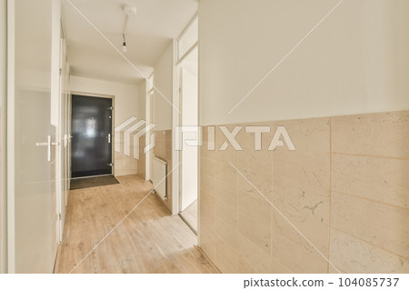 an empty room with wood flooring and white trim on the walls there is a black door in the corner an empty room with wood flooring and white trim on the walls there is a black door in the corner 104085737