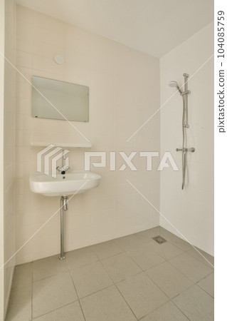 a bathroom with a sink, mirror and shower fauced on the wall next to it is a white tiled floor 104085759