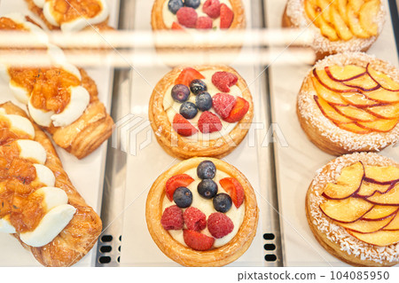 fresh pastries with berries. A variety of fresh pastries in the bakery window. almond croissant is fresh and hot in a cafe next to other types of pastries. The interior of an Italian restaurant. 104085950