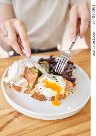 restaurant dish Brioche with poached egg with salmon and avocado. Delicious bread with greens 104086061
