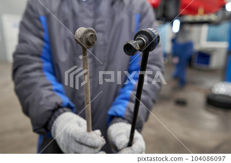 New stabilizer bar or link arm ready to replacement into car suspension on metal table in garage for repair and maintenance. Car part and suspension concept 104086097