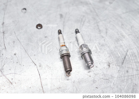 Old and new spark plugs. Comparing spark plugs the maintenance of the engine, on the hands of a mechanic. 104086098