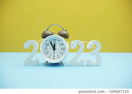 Happy new year 2023 and Alarm clock on blue and yellow background 104087328