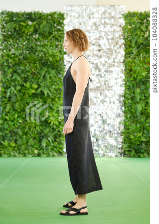 Middle aged woman in linen sundress with straps stands in profile Middle aged woman in linen sundress with straps stands in profile 104088328