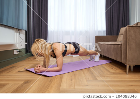 Middle aged woman doing plank exercise at home Middle aged woman doing plank exercise at home 104088346