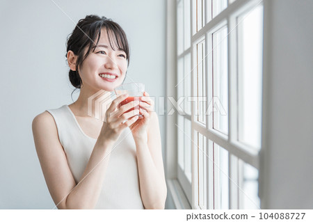 Asian woman drinking red drink in the morning at home (tomato juice, red smoothie, acerola juice) 104088727
