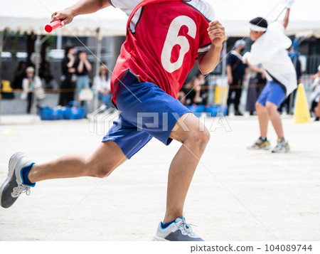 A child running a relay at an elementary school athletic meet A child running a relay at an elementary school athletic meet 104089744