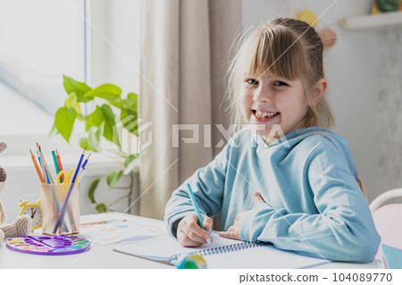 Schooler cute little girl sitting at desk in bedroom, holding pencil, doing homework, kid studying at home, writing notes. Home education, homeschooling. Child smiling, happy because of successul task Schooler cute little girl sitting at desk in bedroom, holding pencil, doing homework, kid studying at home, writing notes. Home education, homeschooling. Child smiling, happy because of successul task 104089770