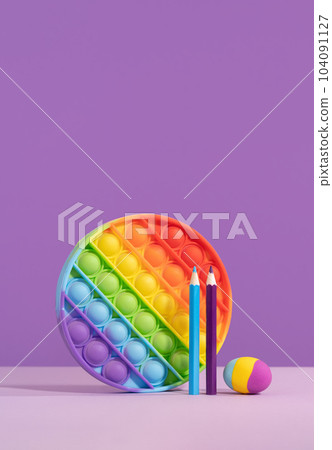 Colored pop it pad with eraser pencils on lilac purple background with rocket. stationery with copy space for back to school or education and craft concept. Bright minimal. Success achievement ideas 104091127