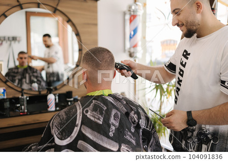 Handsome man on a haircut in the barber sits on a chair. 104091836