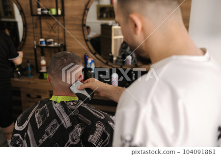 Rear view shot of hairdresser cutting hair of male client. Barber shop Rear view shot of hairdresser cutting hair of male client. Barber shop 104091861