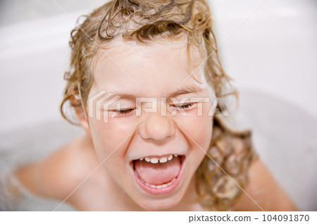 Cute child with shampoo foam and bubbles on hair taking bath. Portrait of happy smiling preschool girl health care and hygiene concept. Washes hair by herself. Cute child with shampoo foam and bubbles on hair taking bath. Portrait of happy smiling preschool girl health care and hygiene concept. Washes hair by herself. 104091870