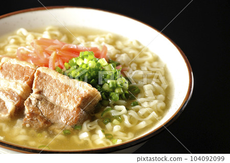 Okinawa soba with pork ribs, plenty of small green onions and red pickled ginger, photographed against a black background Okinawa soba with pork ribs, plenty of small green onions and red pickled ginger, photographed against a black background 104092099