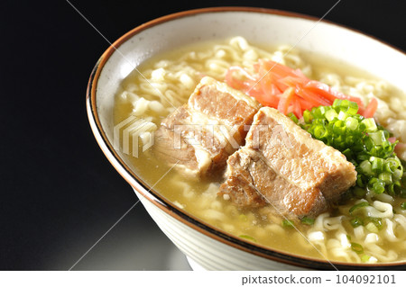 Okinawa soba with pork ribs, plenty of small green onions and red pickled ginger, photographed against a black background Okinawa soba with pork ribs, plenty of small green onions and red pickled ginger, photographed against a black background 104092101