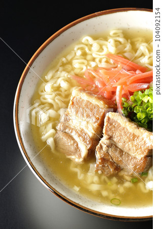 A bird's-eye view of Okinawa soba with pork ribs, plenty of small green onions and pickled ginger on a black background 104092154