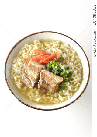 A bird's-eye view of Okinawa soba with pork ribs, plenty of small green onions, and pickled ginger on a white background 104092318
