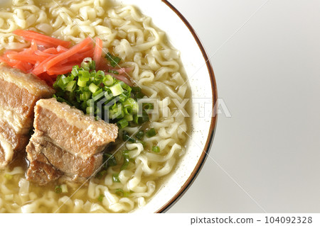 A bird's-eye view of Okinawa soba with pork ribs, plenty of small green onions, and pickled ginger on a white background 104092328