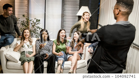 Joyful ladies looking at black male friend dancing in living room 104092741