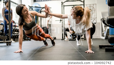 Happy sportswomen giving high five while doing plank exercise Happy sportswomen giving high five while doing plank exercise 104092742