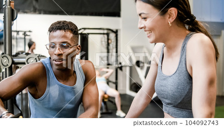 Fit trainer explaining exercise to woman in gym Fit trainer explaining exercise to woman in gym 104092743