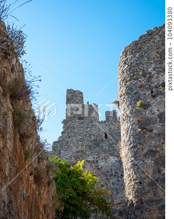 A rocky wall of a castle of Alanya city, ruins with bushes 104093380